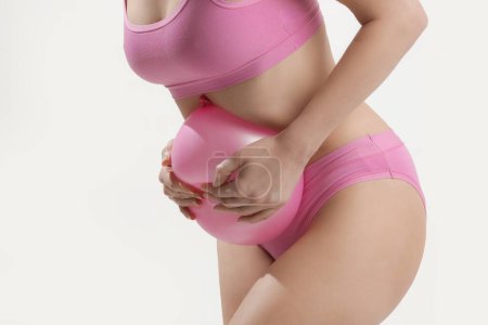 Jeune femme tenant un ballon comme signe d'un gonflement de l'estomac, ballonnements et crampes menstruelles concept
