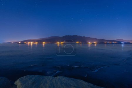 Téléchargez les photos : Un lac gelé la nuit en hiver avec des montagnes en arrière-plan et un ciel plein d'étoiles à Dumulmeori, Yangpyeong, Corée du Sud. - en image libre de droit