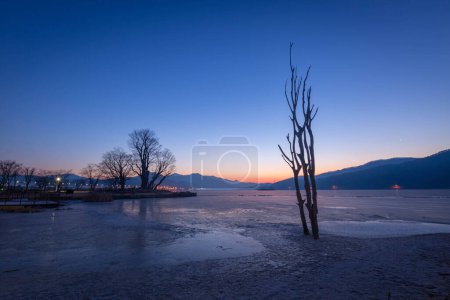 Foto de Lago congelado en Corea del Sur en invierno al amanecer y árboles grandes en el fondo en Dumulmeori, Yangpyeong, Corea del Sur. - Imagen libre de derechos
