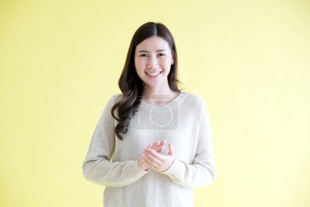 Photo for Young asian woman applausing her hand to congratulation while standing over isolated yellow background - Royalty Free Image