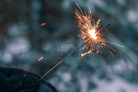 Foto de Burning Sparklers in a Hand Al aire libre en invierno por la noche. Fiesta de celebración de Año Nuevo - Imagen libre de derechos