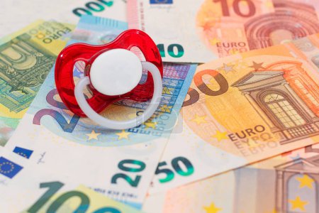 Foto de Childfree, Anticoncepción and Birth Control Concept: Baby Pacifier on the Euro Banknotes (en inglés). Tener hijos es caro y poco rentable - Imagen libre de derechos