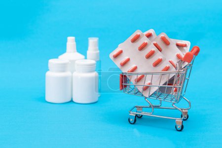 Photo for Buying Medicines. Expensive Medicine and Inflation Concept: Pills and Capsules in Shopping Cart on Blue Background. Global Pharmaceutical Industry and Big Pharma. Ordering Pharmaceutical Products - Royalty Free Image