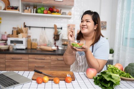 Photo for Asian Pregnant learn how to cook healthy meals from the Internet in kitchen, Fat women prepare a vegetable salad for diet food and lose weight. Concept of healthy eating - Royalty Free Image