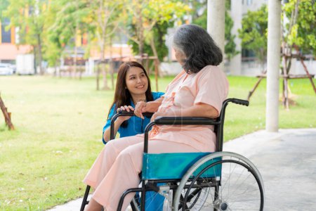 Photo for Asian careful caregiver or nurse hold the patient hand and encourage the patient in a wheelchair.  Concept of happy retirement with care from a caregiver and Savings and senior health insurance. - Royalty Free Image