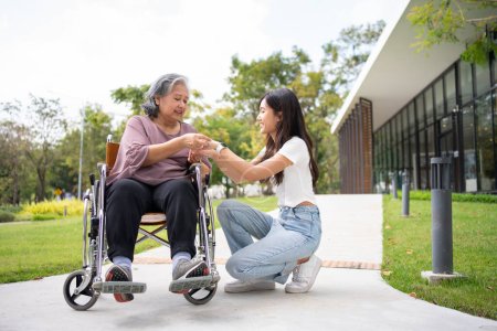 Photo for Asian careful caregiver or nurse hold the patient hand and encourage the patient in a wheelchair. Concept of happy retirement with care from a caregiver and Savings and senior health insurance. - Royalty Free Image