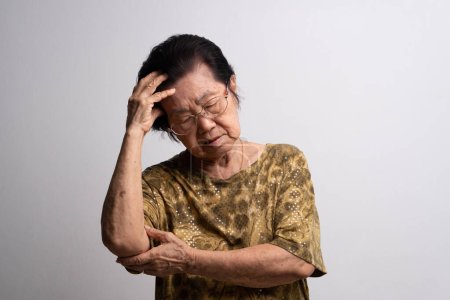 Eine ältere Frau, die starke Kopfschmerzen hat, leidet an einem Schlaganfall, einer Gehirnerkrankung, einer Patientin, die den Kopf mit der Hand hält, an seniler Demenz, Gedächtnisstörungen, verwirrten alten Menschen mit Alzheimer