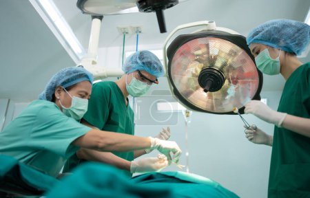 Téléchargez les photos : Équipe de chirurgiens professionnels asiatiques effectuant une chirurgie dans la salle d'opération, chirurgien, assistants et infirmières effectuant une chirurgie sur un patient, concept de traitement du cancer et de la maladie des soins de santé - en image libre de droit