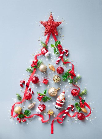 Téléchargez les photos : Fond de Noël composé de branches de sapin, ruban rouge, baies de houx, décorations et lumières. Noël et Nouvel An concept. Vue du dessus - en image libre de droit