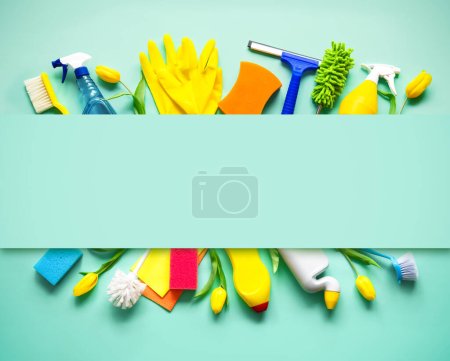 Flat lay composition with cleaning supplies, tools and spring flowers on colorful background. Top view with copy space