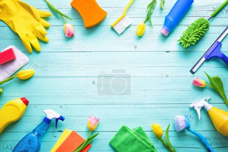Flat lay composition with cleaning supplies, tools and spring flowers on colorful background. Top view with copy space