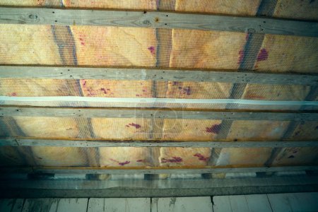 Foto de Suelo de madera aislado entre pisos en una casa privada. Protección de aislamiento acústico y térmico con barrera de vapor y barrera hidroeléctrica. Torneado de madera del techo bajo una capa de lana de vidrio - Imagen libre de derechos