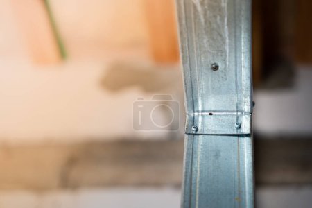 Téléchargez les photos : Close-up of a metal profile frame for a wall. Room divider under construction. Connection using self-tapping screws with a drill. Stiffening ribs in a wall at a construction site - en image libre de droit