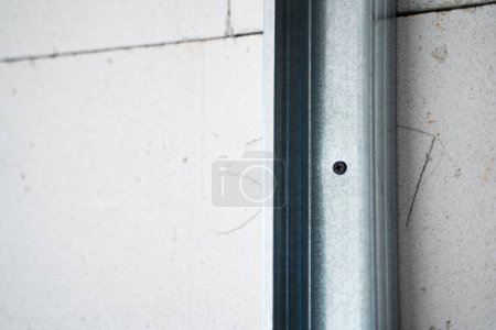 Photo for Fastening a metal U profile to aerated concrete bricks close-up. The metal frame for the partition is screwed to the gas block with a black self-tapping screw. Room divider attached to the wall - Royalty Free Image