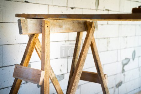 Téléchargez les photos : Wooden homemade scaffolding close-up against the background of a bare aerated concrete wall - en image libre de droit