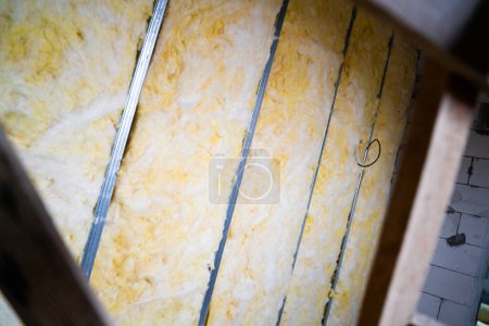Téléchargez les photos : The partition is filled with glass wool. Frame wall from a metal profile with mineral wool close-up. Freshly built interior partition in a private house - en image libre de droit