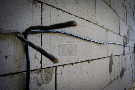 Photo for Divorced electrical wires on bare walls made of aerated concrete bricks. Close-up of the prepared wire for the socket on the wall. Electrical planning in a private house during construction - Royalty Free Image