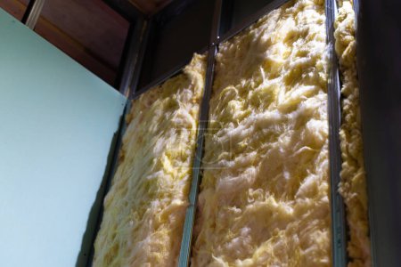 Foto de Frame wall made of metal profile with yellow glass wool insulation. Soundproofing a plasterboard wall with stone wool - Imagen libre de derechos