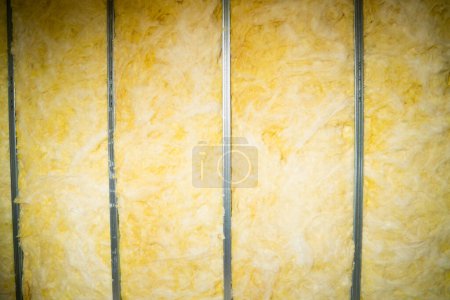 Foto de Rolled glass wool is laid between a metal profile in a frame interior partition. Filling a post-wall with soundproofing - Imagen libre de derechos