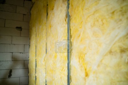 Téléchargez les photos : The partition is filled with glass wool. Frame wall from a metal profile with mineral wool close-up. Freshly built interior partition in a private house - en image libre de droit