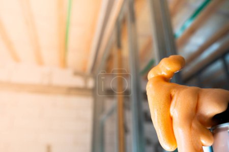 Téléchargez les photos : Mousse de construction en mousse de couleur orange gros plan sur le fond de murs nus dans une maison inachevée. - en image libre de droit