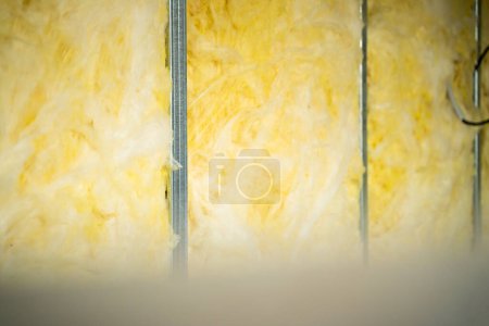 Téléchargez les photos : La laine de verre laminée est posée entre un profil métallique dans une cloison intérieure de cadre. Remplissage d'un post-mur avec insonorisation - en image libre de droit