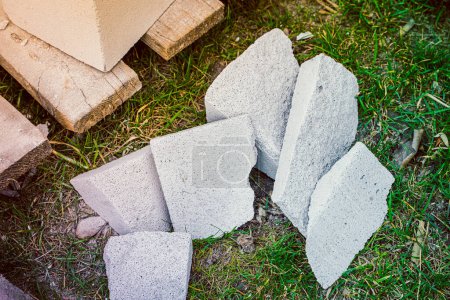 Photo for Shards after cutting aerated concrete lie on the grass. Chipped pieces of aerated concrete bricks on the floor, construction debris - Royalty Free Image