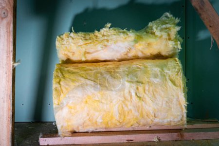 Photo for The remains of a roll of glass wool at a construction site close-up. Yellow mineral wool on the floor against the background of drywall - Royalty Free Image