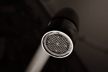 Close-up black and white photo of a water faucet. Old aerator diffuser to save water