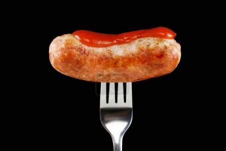 Fried sausage on a fork black background. Food photo
