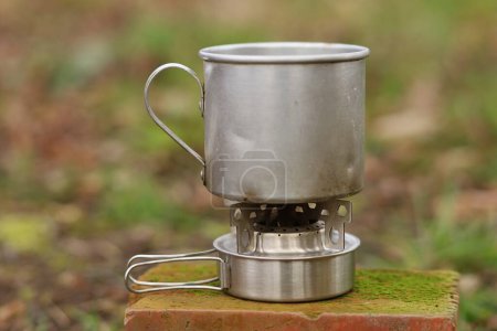 Metal mug on portable camping stove.