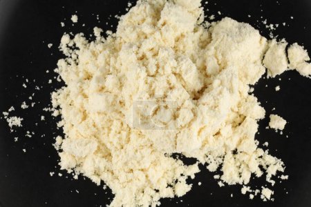 Heap of yellowish protein powder isolated on dark backdrop.