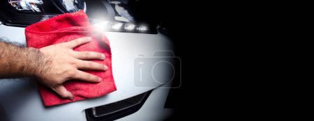 Photo for The owner hand is cleaning the front bumper with a cloth, panoramic banner with copy space on black background - Royalty Free Image