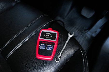 Foto de OBD2 or OBD scanner and wrench on car leather seat for engine system analysis to fixing car engine system , Car maintenance service concept - Imagen libre de derechos