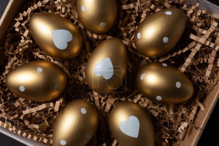 Photo for Close-up view of Golden eggs in paper box on a dark table. - Royalty Free Image