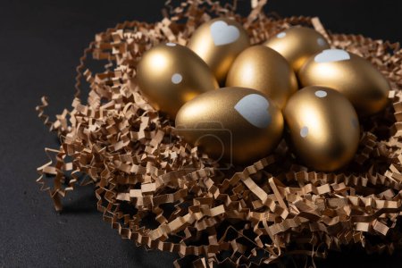 Photo for Gold eggs in paper nest on black background. - Royalty Free Image