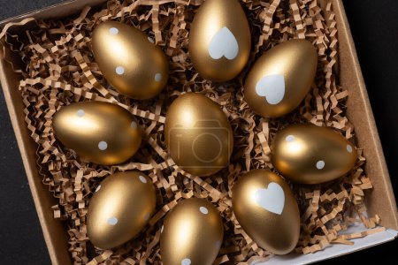 Photo for Golden eggs in paper box on a table. Top view. - Royalty Free Image