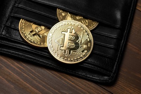 Photo for Cryptocurrency bitcoin gold coins in wallet on wooden background. - Royalty Free Image