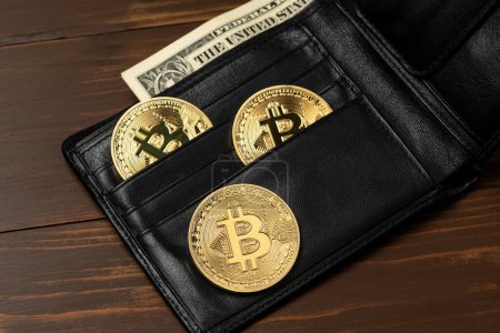 Photo for Bitcoin cryptocurrency gold coins in black wallet on wooden table. - Royalty Free Image