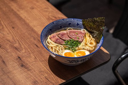 Bowl of japanese ramen noodle soup with beef pastrami on cafe table
