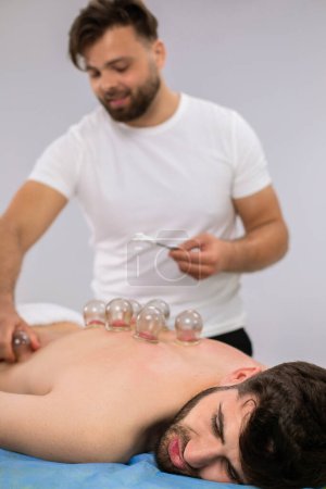 Photo for At spa salon happy client have a back massage with the vacuum cups he feeling relaxed and happy. - Royalty Free Image