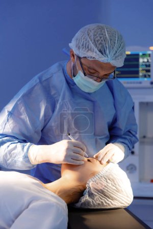 Photo for A surgeon is using a marker to mark something out on a patients eyelid. - Royalty Free Image