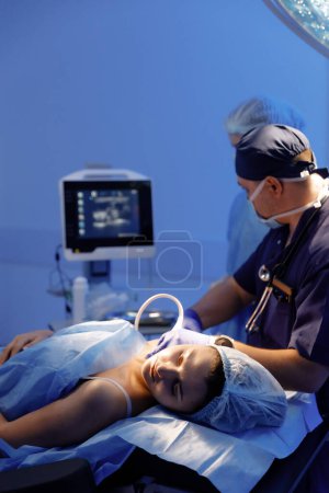 Foto de El anestesiólogo está tomando a una mujer que es paciente sus signos vitales y preparándola para la cirugía. - Imagen libre de derechos