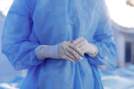 Photo for In the operating room at the hospital capturing video details of surgeon man wearing special equipment and protective gloves holding hands in front of the camera. Hospital - Royalty Free Image