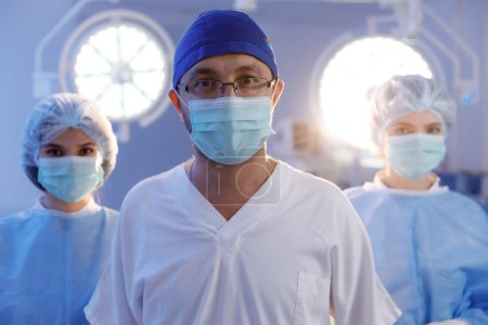 Photo for Portrait of serious diverse surgeons with face masks in operating room in slow motion. Medicine, health and care. Hospital - Royalty Free Image