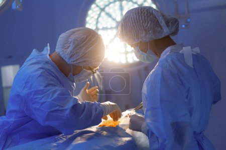 Foto de Un primer plano del cirujano que usa anteojos y se concentra realizando una cirugía en una sala médica. - Imagen libre de derechos