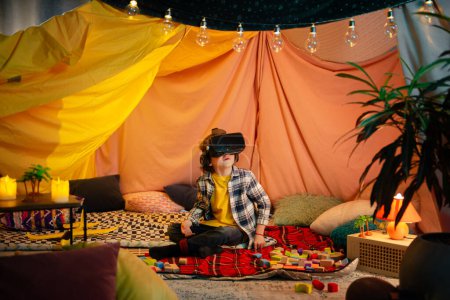Téléchargez les photos : The boy are inside a massive and brightly colored indoor blanket fort while playing together with a vr headset. - en image libre de droit