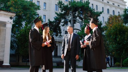 Photo for Happy group of students in the graduation day together with their college professor have a conversation they are excited holding their diplomas in the college garden. Graduate - Royalty Free Image