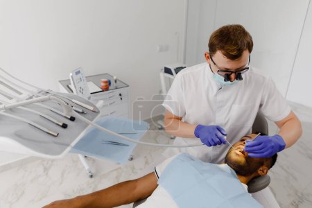 Téléchargez les photos : À la clinique dentaire, le dentiste vérifier les cavités du patient qu'il utilise l'instrument dentaire pour trouver le problème des dents et commencer à faire le traitement. Dentiste - en image libre de droit