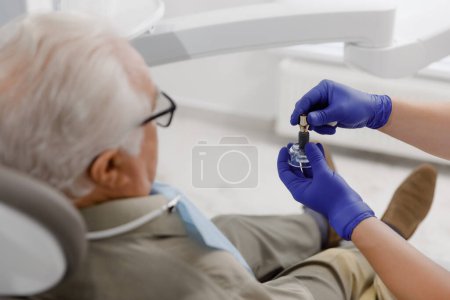 Photo for At dental clinic patient old man sitting on the dentist chair the doctor treating cavities with special dental instruments doctor working very professional. - Royalty Free Image